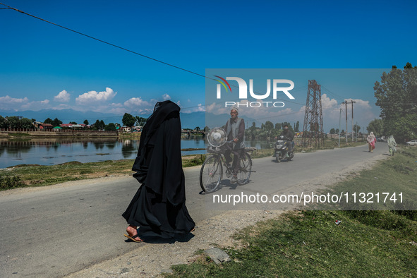 An elderly man is carrying a fan on his bicycle on a hot summer day in Sopore, Baramulla, Jammu and Kashmir, India, on June 11, 2024. 