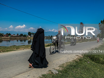 An elderly man is carrying a fan on his bicycle on a hot summer day in Sopore, Baramulla, Jammu and Kashmir, India, on June 11, 2024. (