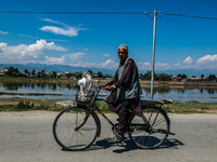 An elderly man is carrying a fan on his bicycle on a hot summer day in Sopore, Baramulla, Jammu and Kashmir, India, on June 11, 2024. (