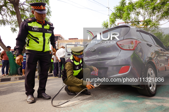 Members of the Lalitpur Metropolitan City Police are inspecting the pollution level of a vehicle by stopping it on the side of a road as a m...