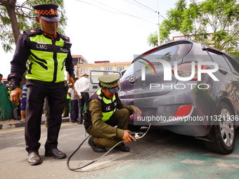 Members of the Lalitpur Metropolitan City Police are inspecting the pollution level of a vehicle by stopping it on the side of a road as a m...