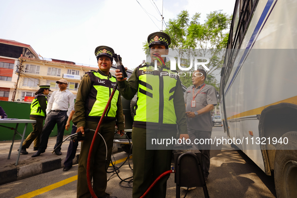 Members of the Lalitpur Metropolitan City Police are inspecting the pollution level of a vehicle by stopping it on the side of a road as a m...