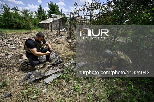 Police officers are recording damage next to a house that is partially destroyed by a Russian drone attack in Orikhiv, Zaporizhzhia region,...