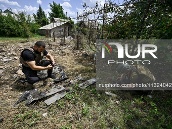 Police officers are recording damage next to a house that is partially destroyed by a Russian drone attack in Orikhiv, Zaporizhzhia region,...