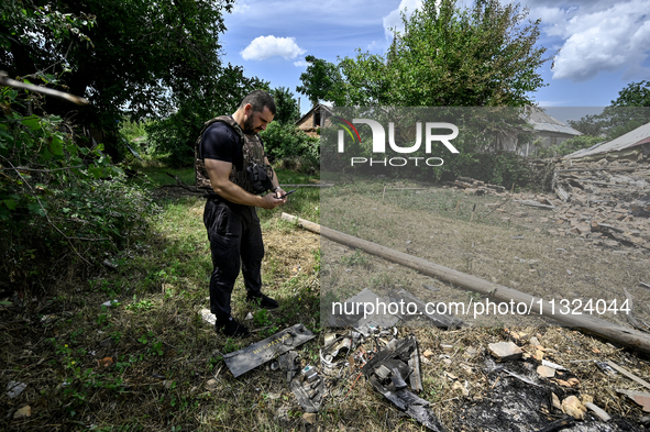 A police officer is recording damage next to a house that is partially destroyed by a Russian drone attack in Orikhiv, Zaporizhzhia region,...