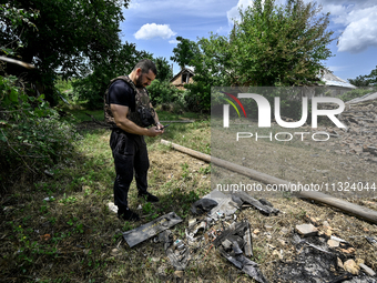 A police officer is recording damage next to a house that is partially destroyed by a Russian drone attack in Orikhiv, Zaporizhzhia region,...