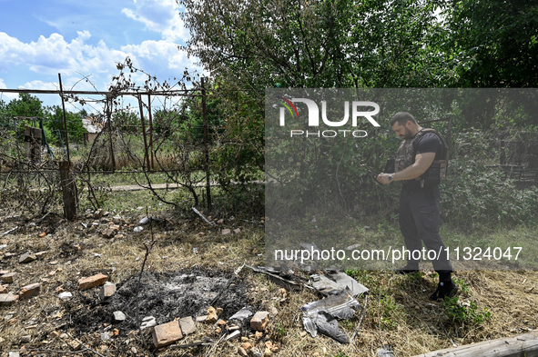 A police officer is recording damage next to a house that is partially destroyed by a Russian drone attack in Orikhiv, Zaporizhzhia region,...