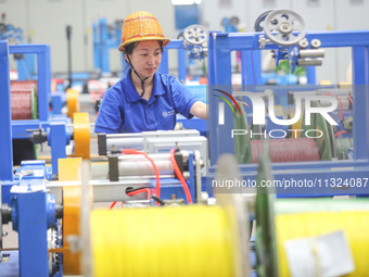 A worker is producing special cable products in Huzhou, China, on June 12, 2024. (