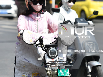 Citizens are wearing sun-protective clothing and riding on a street under high temperatures in Fuyang, China, on June 12, 2024. The Central...