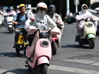 Citizens are wearing sun-protective clothing and riding on a street under high temperatures in Fuyang, China, on June 12, 2024. The Central...