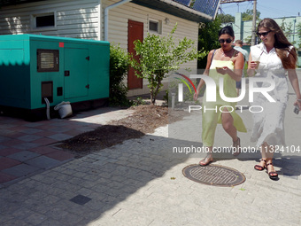 Two women are walking past a generator powering a cafe at the seaside during rolling blackouts in Odesa, Ukraine, on June 11, 2024. NO USE R...