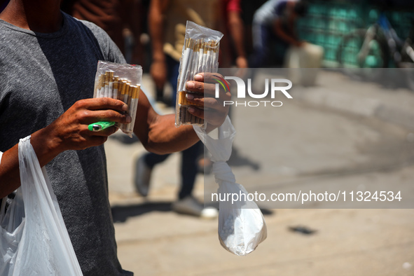 A displaced man is selling hand-rolled cigarettes on a street next to Al-Aqsa Martyrs Hospital in Deir el-Balah, in the central Gaza Strip,...