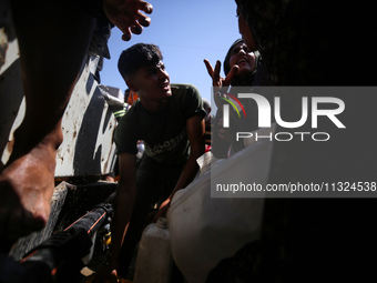 Palestinians are lining up to fill their containers with water on a street next to tents in Deir el-Balah, in the central Gaza Strip, on Jun...