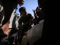 Palestinians are lining up to fill their containers with water on a street next to tents in Deir el-Balah, in the central Gaza Strip, on Jun...