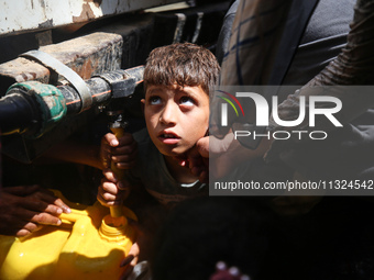 Palestinians are lining up to fill their containers with water on a street next to tents in Deir el-Balah, in the central Gaza Strip, on Jun...