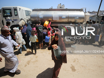 Palestinians are lining up to fill their containers with water on a street next to tents in Deir el-Balah, in the central Gaza Strip, on Jun...