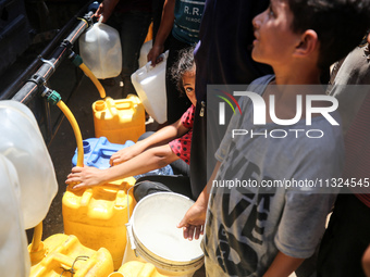 Palestinians are lining up to fill their containers with water on a street next to tents in Deir el-Balah, in the central Gaza Strip, on Jun...