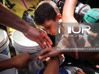 Palestinians are lining up to fill their containers with water on a street next to tents in Deir el-Balah, in the central Gaza Strip, on Jun...