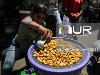 A displaced girl is selling lupin beans and waiting for customers on a street next to Al-Aqsa Martyrs Hospital in Deir el-Balah, in the cent...