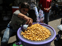 A displaced girl is selling lupin beans and waiting for customers on a street next to Al-Aqsa Martyrs Hospital in Deir el-Balah, in the cent...