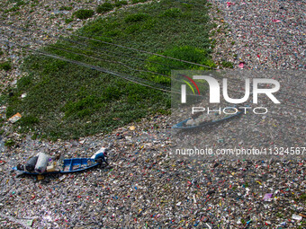 Residents on boats are collecting recyclable plastics from the heavily polluted Citarum River in Batujajar, Bandung, West Java, Indonesia, o...