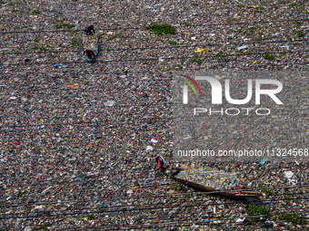 Residents on boats are collecting recyclable plastics from the heavily polluted Citarum River in Batujajar, Bandung, West Java, Indonesia, o...