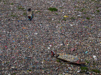 Residents on boats are collecting recyclable plastics from the heavily polluted Citarum River in Batujajar, Bandung, West Java, Indonesia, o...