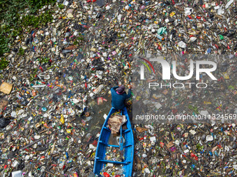 Residents on boats are collecting recyclable plastics from the heavily polluted Citarum River in Batujajar, Bandung, West Java, Indonesia, o...