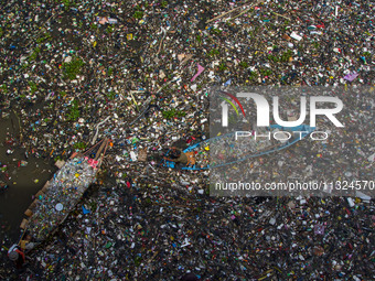 Residents on boats are collecting recyclable plastics from the heavily polluted Citarum River in Batujajar, Bandung, West Java, Indonesia, o...