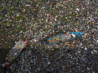 Residents on boats are collecting recyclable plastics from the heavily polluted Citarum River in Batujajar, Bandung, West Java, Indonesia, o...