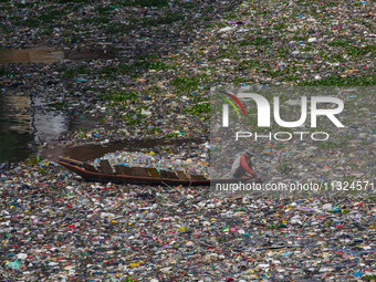 Residents on boats are collecting recyclable plastics from the heavily polluted Citarum River in Batujajar, Bandung, West Java, Indonesia, o...