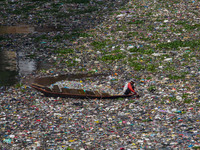 Residents on boats are collecting recyclable plastics from the heavily polluted Citarum River in Batujajar, Bandung, West Java, Indonesia, o...