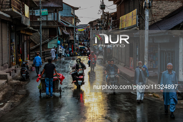 Commuters are walking after light rainfall in Sopore, Jammu and Kashmir, India, on June 12, 2024 