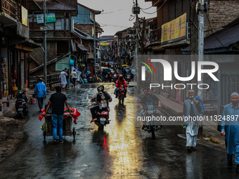 Commuters are walking after light rainfall in Sopore, Jammu and Kashmir, India, on June 12, 2024 (