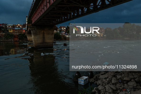 A young man is catching fish on the banks of River Jhelum after light rainfall in Sopore, Jammu and Kashmir, India, on June 12, 2024 