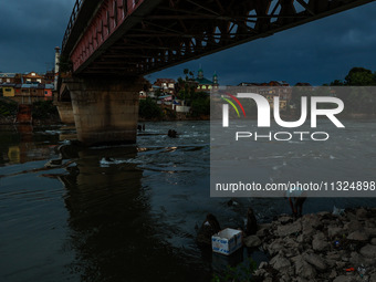 A young man is catching fish on the banks of River Jhelum after light rainfall in Sopore, Jammu and Kashmir, India, on June 12, 2024 (