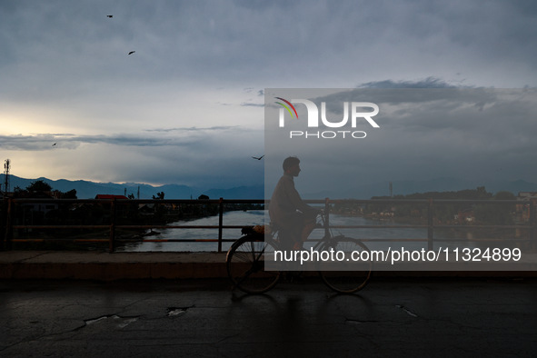 A man is riding his bicycle after light rainfall in Sopore, Jammu and Kashmir, India, on June 12, 2024 