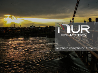 People are walking on a bridge during sunset after light rainfall in Sopore, Jammu and Kashmir, India, on June 12, 2024 (