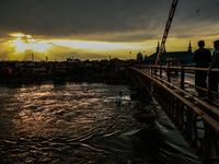 People are walking on a bridge during sunset after light rainfall in Sopore, Jammu and Kashmir, India, on June 12, 2024 (