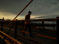 People are walking on a bridge during sunset after light rainfall in Sopore, Jammu and Kashmir, India, on June 12, 2024 (