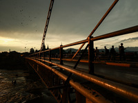 People are walking on a bridge during sunset after light rainfall in Sopore, Jammu and Kashmir, India, on June 12, 2024 (