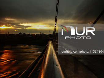 People are walking on a bridge during sunset after light rainfall in Sopore, Jammu and Kashmir, India, on June 12, 2024 (