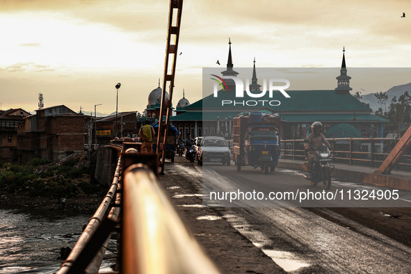 People are walking on a bridge during sunset after light rainfall in Sopore, Jammu and Kashmir, India, on June 12, 2024 