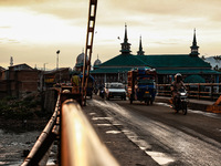 People are walking on a bridge during sunset after light rainfall in Sopore, Jammu and Kashmir, India, on June 12, 2024 (