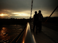 People are walking on a bridge during sunset after light rainfall in Sopore, Jammu and Kashmir, India, on June 12, 2024 (