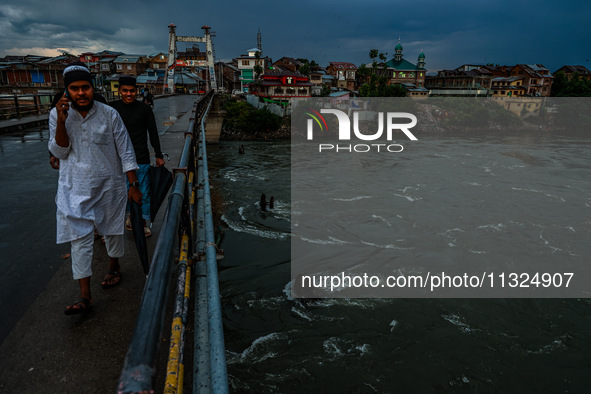 Muslim boys are walking on a bridge after light rainfall in Sopore, Jammu and Kashmir, India, on June 12, 2024 