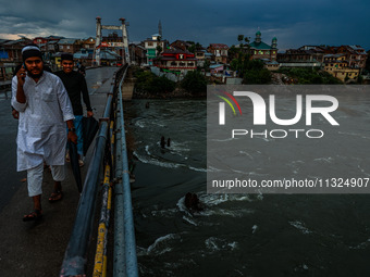 Muslim boys are walking on a bridge after light rainfall in Sopore, Jammu and Kashmir, India, on June 12, 2024 (