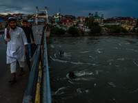 Muslim boys are walking on a bridge after light rainfall in Sopore, Jammu and Kashmir, India, on June 12, 2024 (