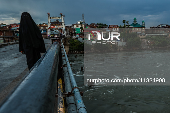 A woman is wearing a Burqa (Hijab) and walking on a bridge after light rainfall in Sopore, Jammu and Kashmir, India, on June 12, 2024. 