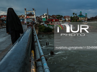 A woman is wearing a Burqa (Hijab) and walking on a bridge after light rainfall in Sopore, Jammu and Kashmir, India, on June 12, 2024. (